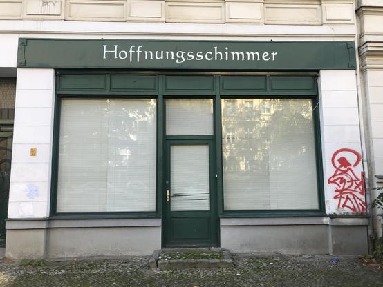 Ein Geschäft, sieht verrammelt aus. Schild darüber verheißt: Hoffnungsschimmer.