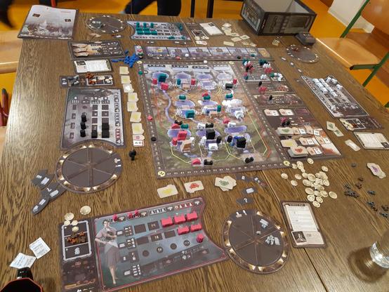 Aufgebautes Brettspiel Wasserkraft. In der Mitte der Spielplan mit Staudämmen Rohren und Turbinenhäusern in verschiedenen Farben. Rechts davon ein Aktionstableu mit diversen eingesetzten arbeiterfiguren. Im Vordergrund das Spielertableau der Farbe Rot.
