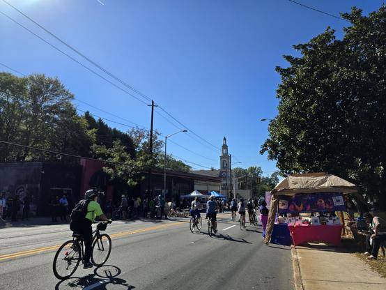 People walk and bike on a street closed to cars on a sunny day