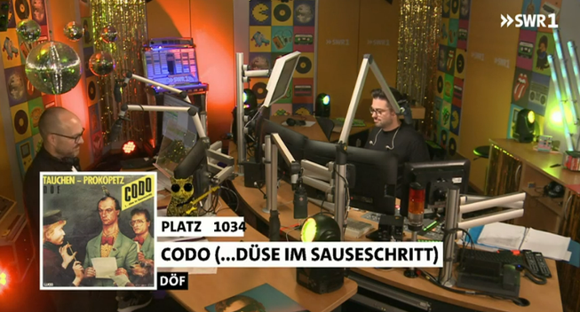 Ein Screenshot aus einem Aufnahmestudio des SWR1. Am linken unteren Eck ist der Titel des aktuell gespielten Liedes eingeblendet.
