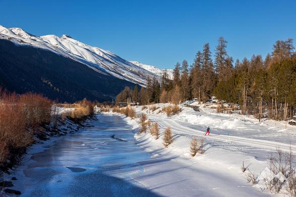 Groomed trail next to a river in the morning sun.