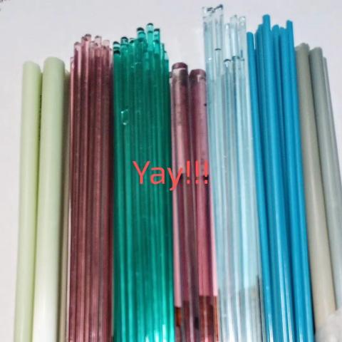 Image of some new colors of soft lampworking glass rods and stringers, in shades of purple, pale blue, opaque teal, and light greens.