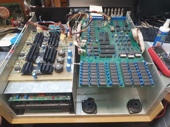 A large metal computer case, about 50 cm wide, with the cover off. The box is divided into two halves. On the left is an exposed power supply, with an 8 inch tape drive mounted below it. On the right are the two motherboards, one hidden below the other. Below the motherboards are a large open space to fit the hard drive.