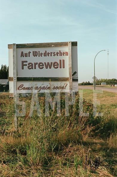 A photograph, shot by Mark, on re-spooled aerial surveillance film depicting the "Auf Wiedersehen" sign at the eastern edge of Humboldt in Saskatchewan, Canada