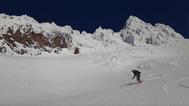 Bright blue sky above, rocky jagged rocks rise above. Fresh snow covering everything like a fresh layer of thick paint. Splitboarding making turns down my favorite run on Mt Hood!