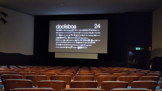 Room 3 of the S. Jorge Cinema in Lisbon before the session. The screen displays a lot of logos from supporters of the festival. People have not yet arrived. The classy wooden seats are still empty.