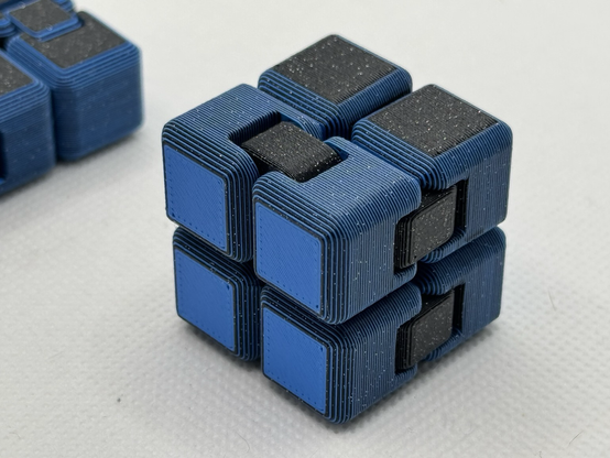 A black and blue fidget cube with color changes on every layer with some bits colored solid black.