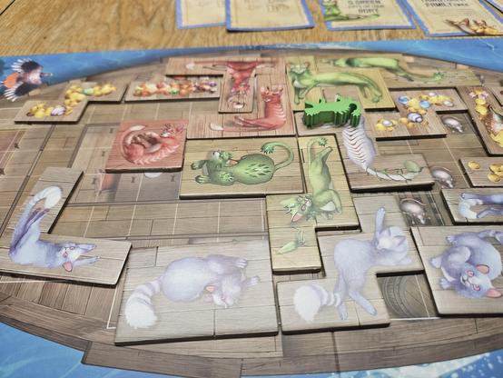 Photograph of Isle of cats game board. Cats in the shape of Tetris/puzzle pieces lay on a ship.