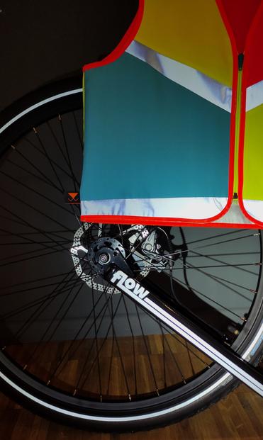 Hinterrad eines großen Tretrollers mit reflektierendem Sticker und Warnweste