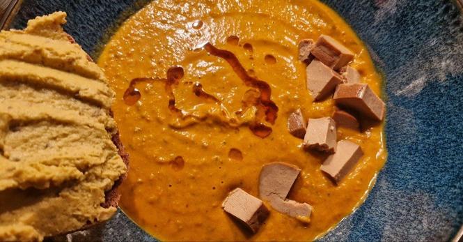 Grosse Suppenschüssel. Fertige Suppe mit geräuchertem Tofu, Klecks geröstetes Sesamöl, Vollkornbrot mit Erbsen-"Hummus"