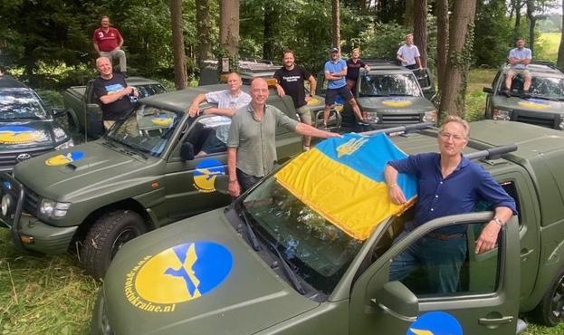 Vrijwilligers van de stichting rondom een aantal gedoneerde militaire auto's.