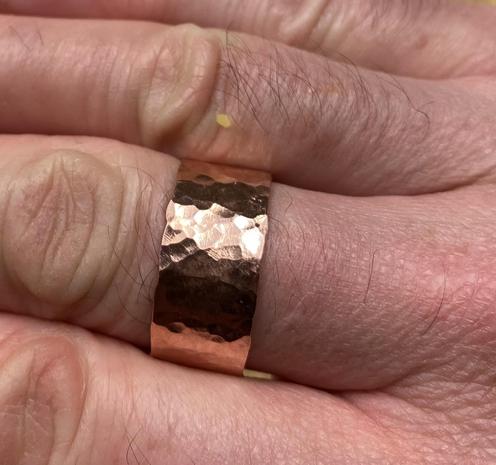 A polished copper ring on a middle finger.