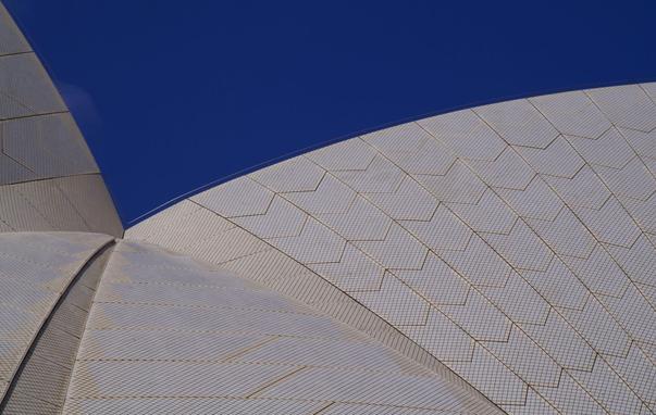 Image of the curved, tiled sails of the Sydney Opera House. The sails intersect at different angles forming a set of complex curved shapes.