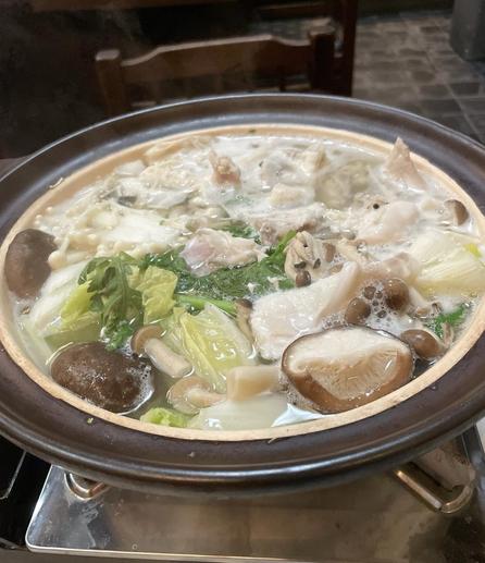 Photo of a hotpot brimming with vegetables, mushrooms and pieces of white fish (blowfish)