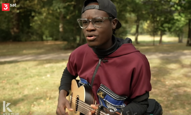 Der schwarze Sänger mit Gitarre in einem Park