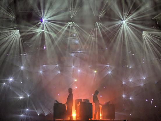 Two men on stage, surrounded by lights that look like stars.