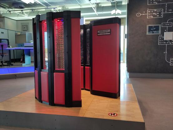 A Cray 2 computer. It is red and black and consists of modules which are a little higher than 1 meter and which are arranged in an arc of a circle.