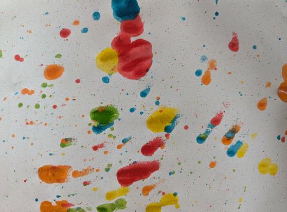 White paper with different coloured blobs of paint flicked onto it.