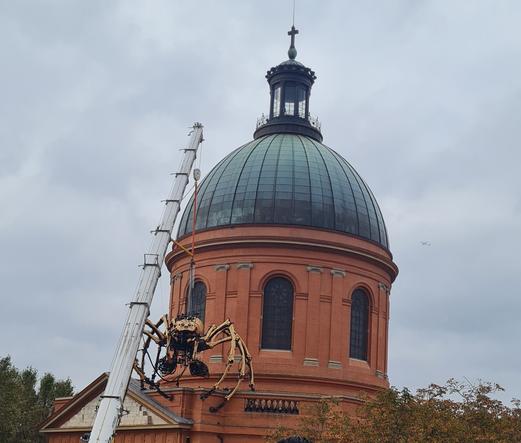 Une araignée mécanique portée par une grue sur le dôme de la Grave, un bâtiment en briques surmonté d'une coupole