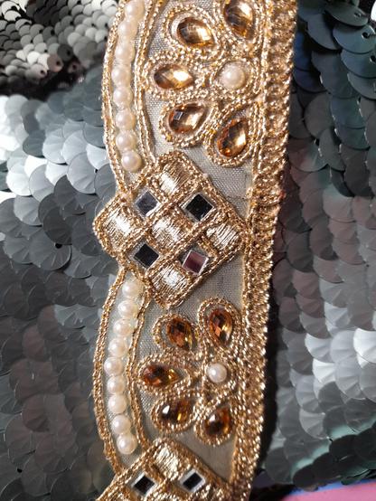 A large braid with floral elements embroidered with gold, Wax beads, tiny mirrors and glass vignettes.