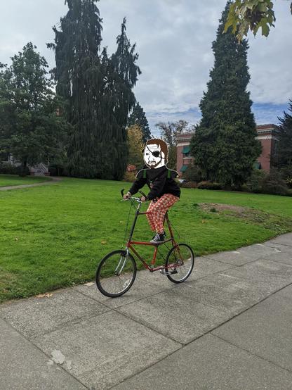 Person riding a red tall bike one the U of O campus