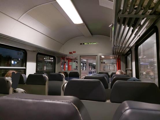 Sicht über die Sitzreihen in einem n-Wagen mit DBM-Design. Über der Schiebetür wird im FIS "RE8 Stuttgart" angezeigt.