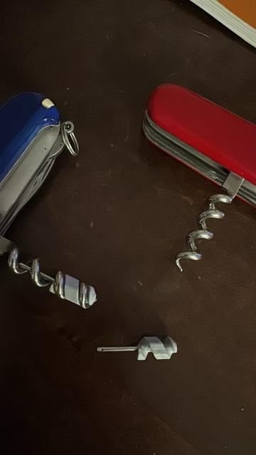 Foto zweier Victorinoxtaschenmesser mit herausgeklappten Korken zieren. Der Mini Schraubenzieher eines Messers ist herausgedreht und liegt daneben.