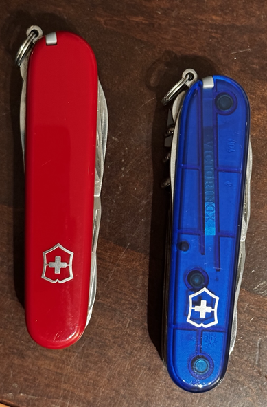 Zwei Schweizer Taschenmesser, links in Rot, rechts in Blau.
