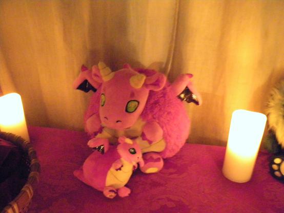 An image of two red and yellow dragons -- one big and one small. The big one is embracing the small one. They are surrounded by candles.