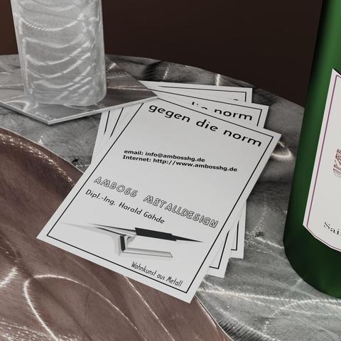 Faltblätter liegen auf einer geflexten Stahloberfläche, auf einer Ecke steht eine Edelstahlvase und auf der anderen Seite ist noch ein Teil einer Rotweinflasche zu sehen.

Leaflets lie on a sanded steel surface, a stainless steel vase stands on one corner and part of a red wine bottle can still be seen on the other side.