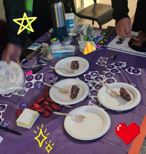 A table with purple tablecloth and candies, stickers and 3 plates with cake on them and one empty.