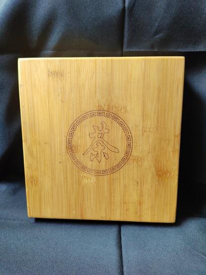 Since I found a tea brick, I decided, too, to clean off my tea storage box and tray.  The picture depicts the tray in the box and the top/front of the box showing facing the camera.  The box and tray combination is made of bamboo and is typically stored horizontally, not vertically like this.  It was arranged this way for ease of photography and for continuity with the next photograph.

The top of the bamboo box is branded with the Chinese word for tea in a fancy scrollwork circle.