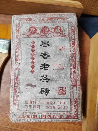 The tea brick, still wrapped, from the front.  The big, black Chinese characters running down the centre say "jujube scented old tea brick".  (No jujubes were harmed in the making of this tea.  The descriptive text is for comparison purposes only in the same vein as an astringent wine being described as tasting like walnuts.)

The red text to the bottom left reads "Menghai mellow aged pu'er" while to the right it reads "pu'er tea (cooked tea) net contents: 250 grams".