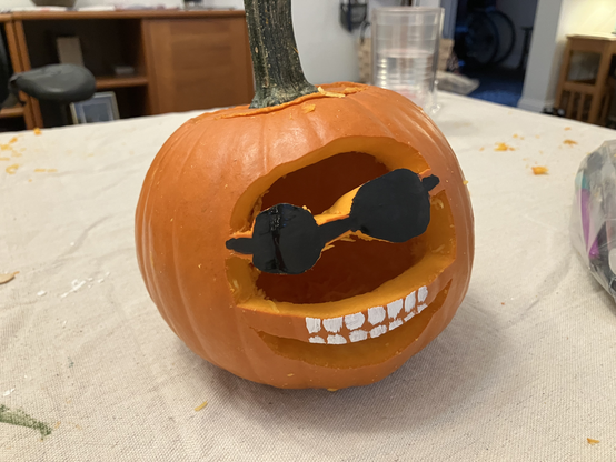 Picture of a carved pumpkin.  It has painted-black sunglasses and an alarming number of painted-white teeth.