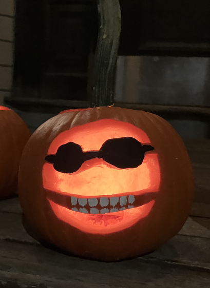 That same pumpkin, lit at night and glowing from within.  The sunglasses and teeth remain visible.