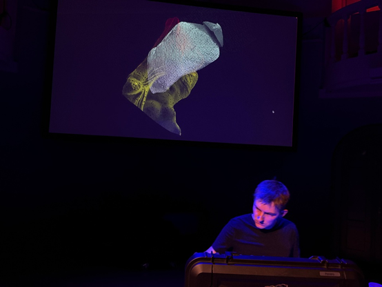 Me playing a modular synth in front of a glitched 3D scan