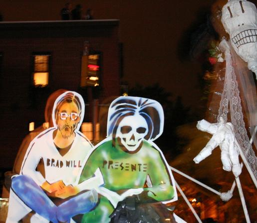 Poster of Will at the 2006 New York City Halloween Parade. Will is depicted in a white shirt, with his name across the front, glasses and scruffy beard. His arms are linked with symbolic Death, in a green shirt, with a skull instead of a face. Death’s shirt reads: Presente.  By Patrick Gruban - Flickr, CC BY-SA 2.0, https://commons.wikimedia.org/w/index.php?curid=3178542