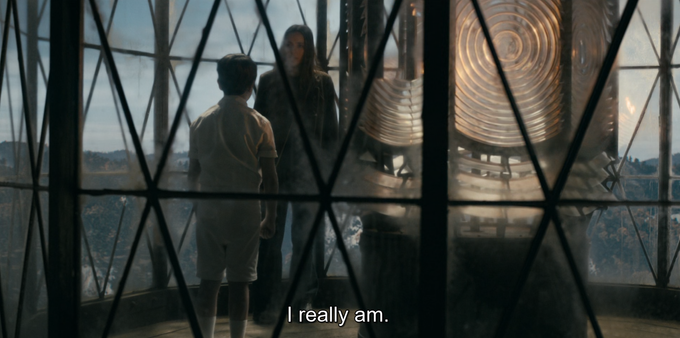 Screenshot from the paranormal TV drama "From," here of a ghostly looking child in an Edwardian tennis outfit, standing on the upper platform of a mysterious lighthouse overlooking a massive cove, because of course!