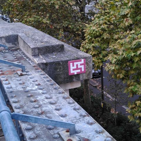 Une mosaïque blancge et rouge représentant une espèce de labyrinthe, collée sur un ancien pont ferroviaire.