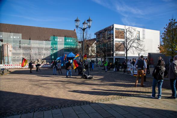 Die Personen der Versammlung auf einem großen Platz unter blauem Himmel.