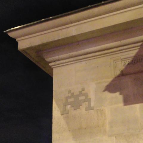 Une mosaïque beige représentant un space invader, appliquée sur un bâtiment public de la même couleur : un vrai fantôme, très discret !