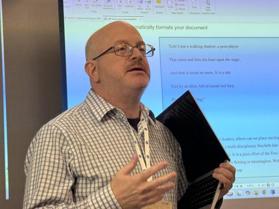 A man giving a talk in front of a projection screen.