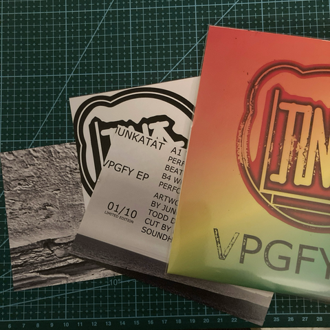 7” vinyl in rainbow sleeve with circular logo for Junkatat VPGFY EP. There are also 3 inserts, 1 black and white photo, 1 list of credits and one logo on a cutting mat.