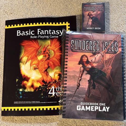 Print on demand copy of the Basic Fantasy Role-Playing Game next to the Sundered Isles game books and the Sundered Isles asset deck of cards.