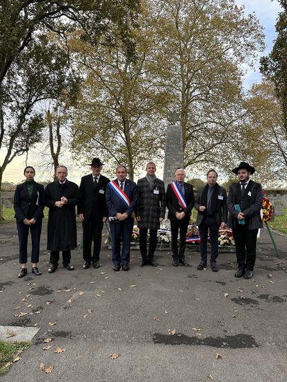 Die Teilnehmerinnen und Teilnehmer der Gedenkveranstaltung stehen vor dem Gedenkstein auf dem Deportiertenfriedhof im französischen Gurs
