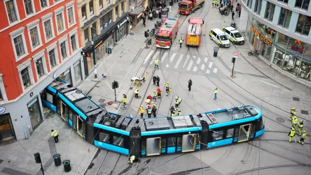 An articulated 5-section tram at a T-intersection derailed and instead of turning left went straight into a building. The front of it is in a 1-st floor store. Debris below the tram, likely glass and concrete.