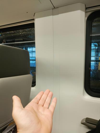 Photograph of my open palmed hand outstretched to behold the beautiful bulkhead of VIA Rails new carriages. FTP.
