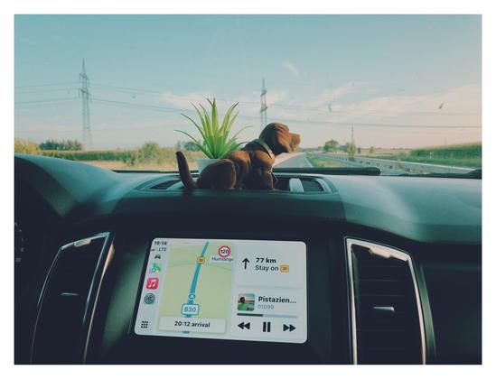View out of a windscreen with a navigation system in front, showing music and navigation.