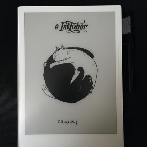 A photo of the same black and white drawing of 2 cats slepping together, on the e-ink tablet it was drawn.