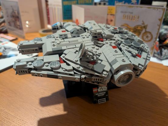A 25cm long Millennium Falcon made of Lego. It's on a small stand and is marked as a 25th anniversary edition.